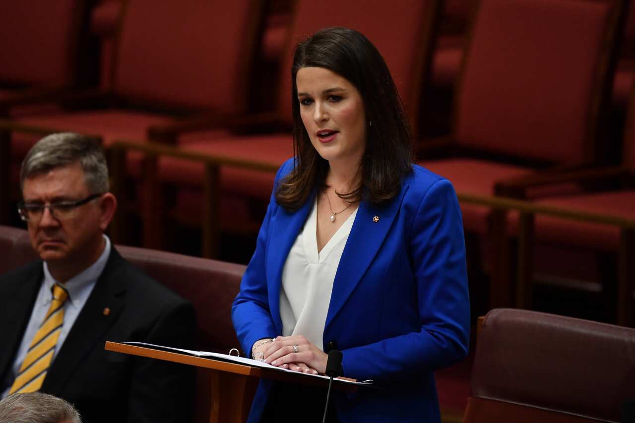 Woman in blue suit stands at a lectern.