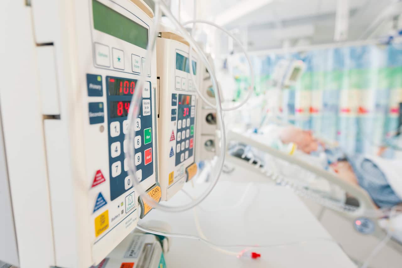 A patient in the intensive care unit of a hospital, surrounded by machines.