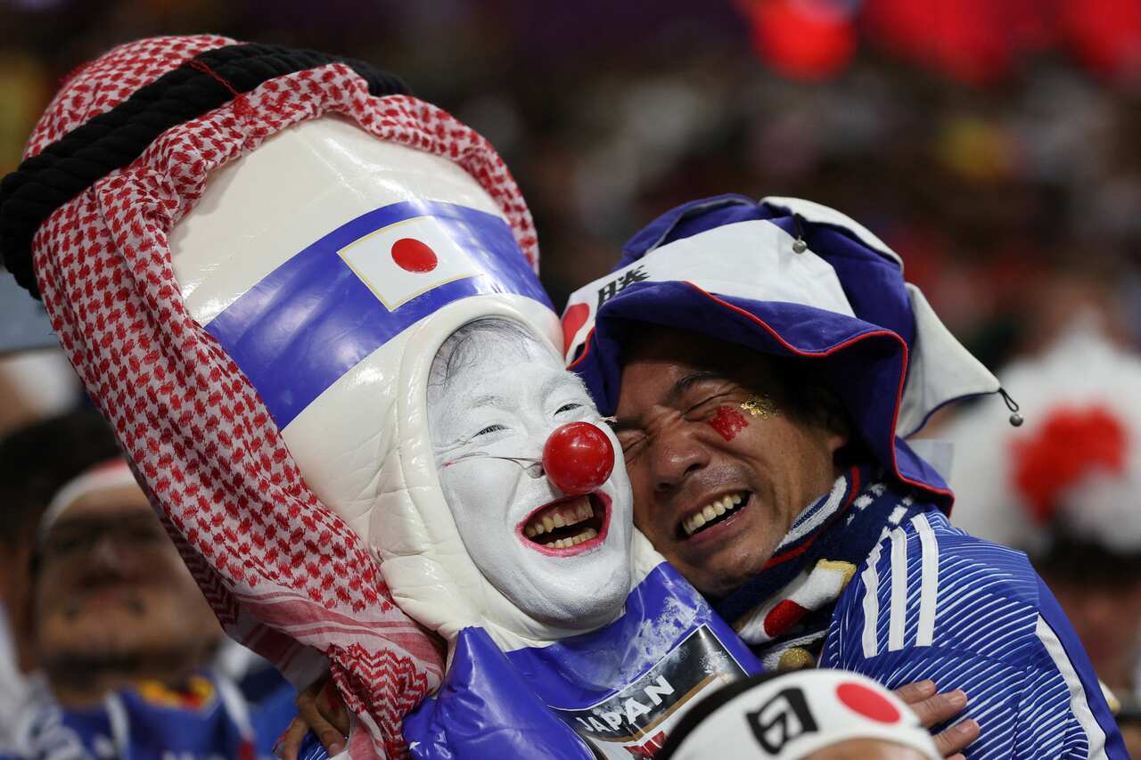 A person dressed as a clown and a fan celebrate and hug. 