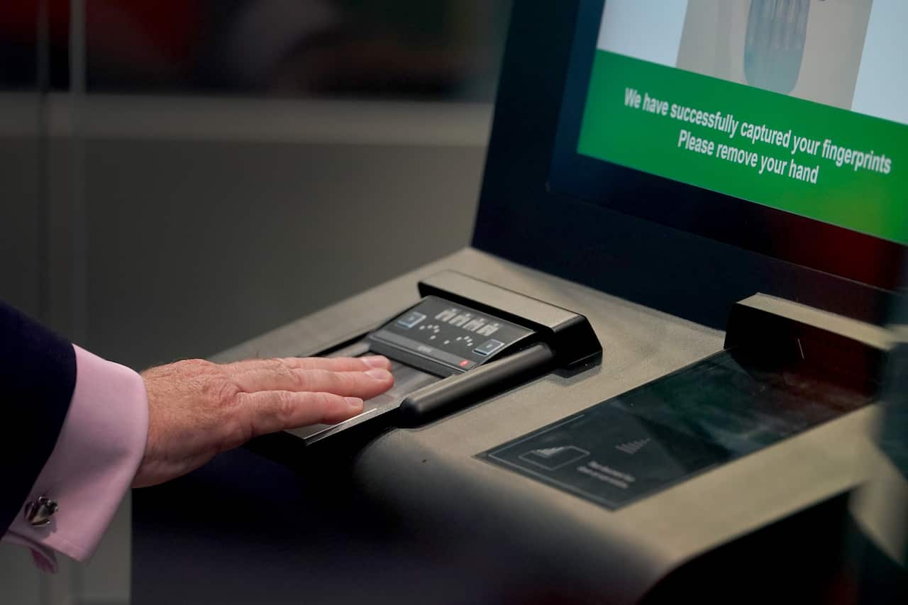 A man placing his hand on an electronic scanner, having his fingerprints taken.