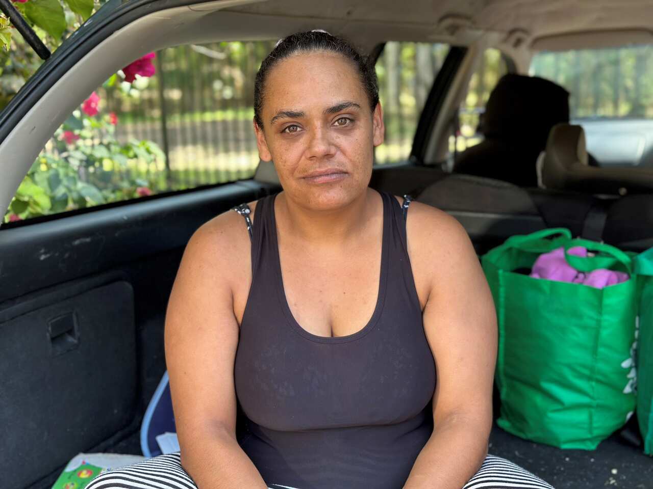 A woman sitting in the back of her car with some bags