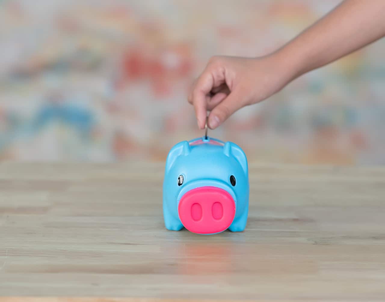 Close-up of a young woman's hand putting a coin in a piggy bank, ideas and financial growth