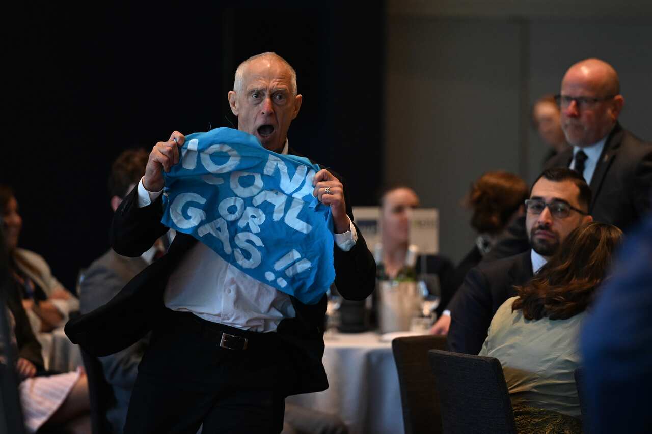 A man in a suit holds up a no coal and gas banner.