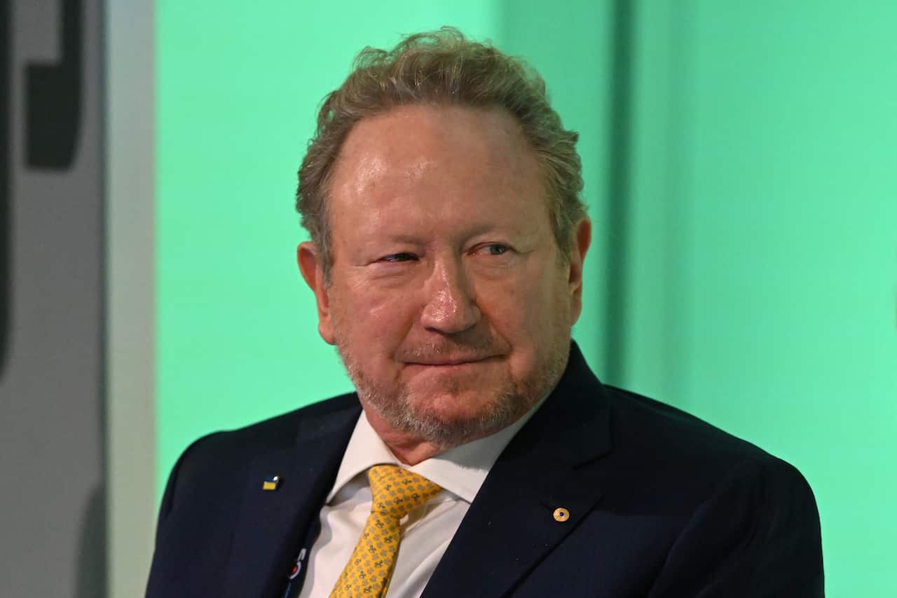 A man sitting in front of a blue-green background.