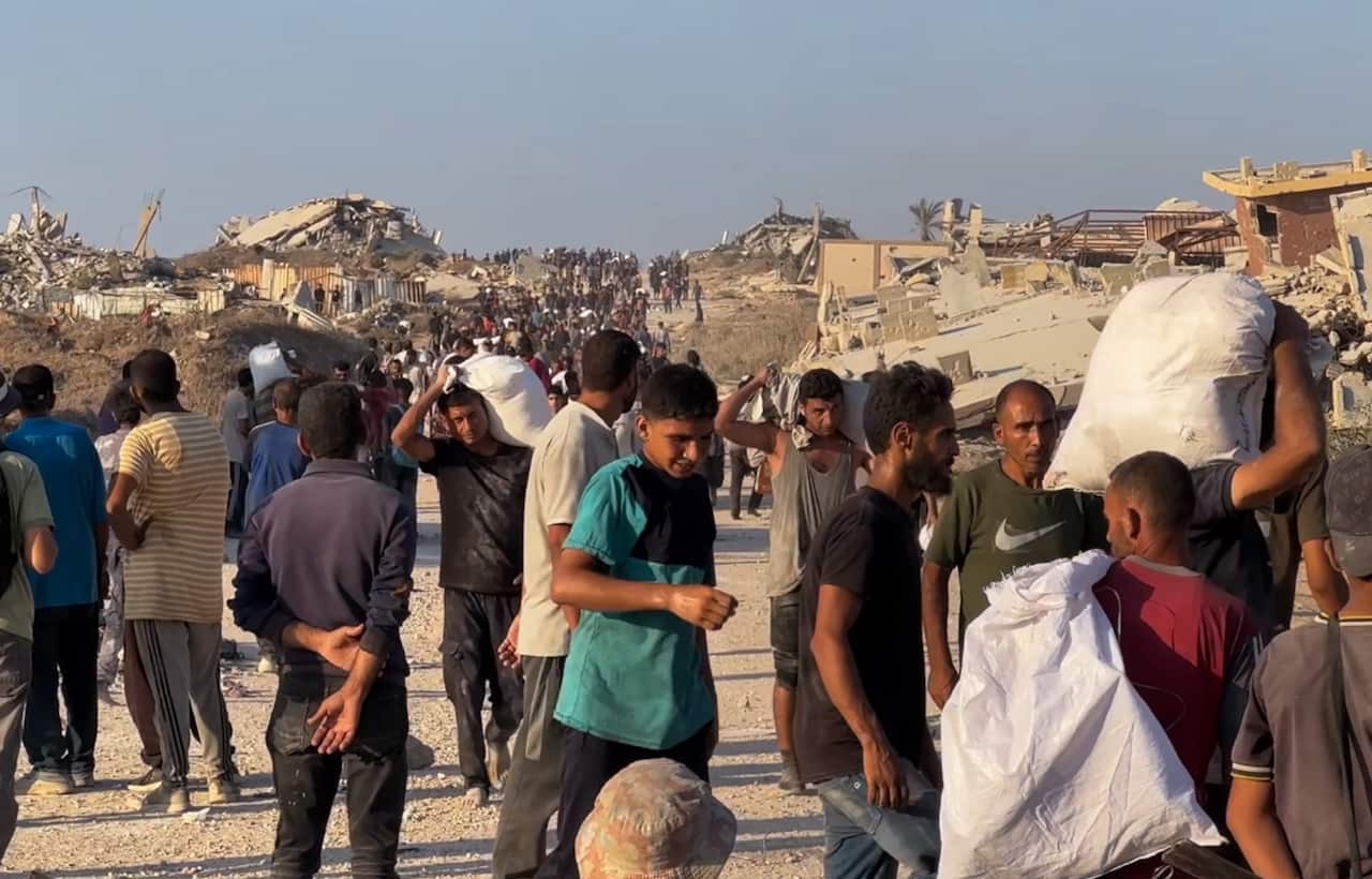 Group of people walking with bags, presumably containing food and other supplies.