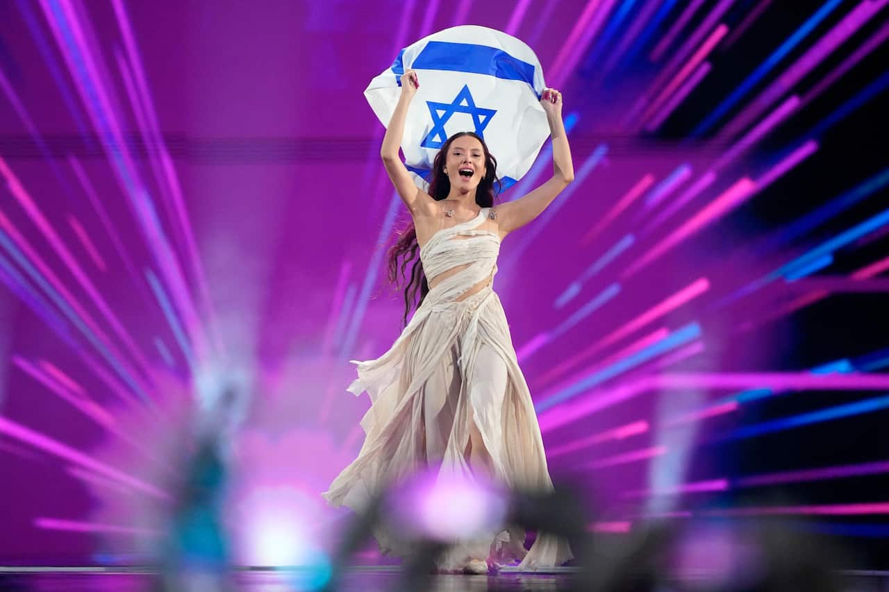 A woman on stage holds up a flag