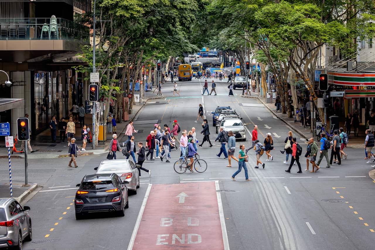Pedestrians cross a busy intersection in the city