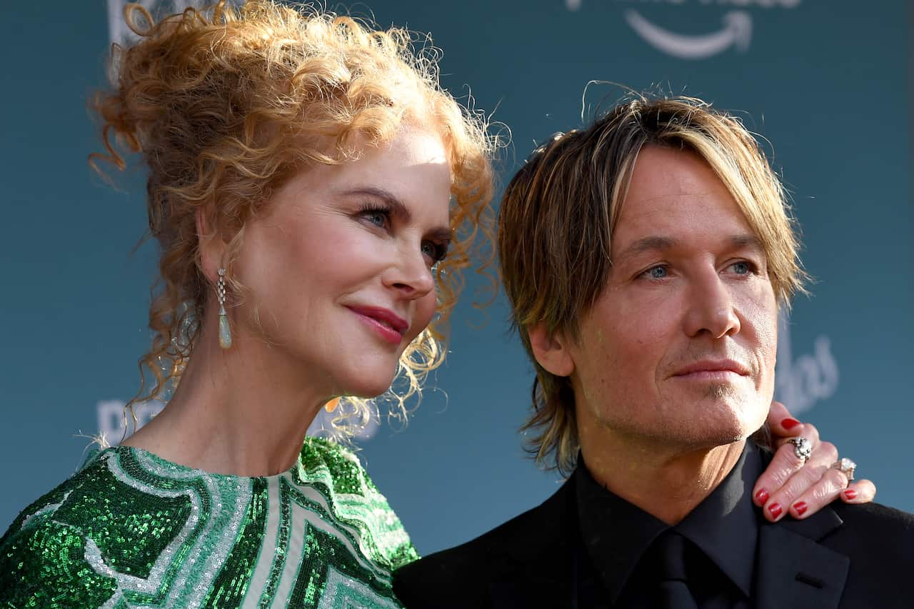 Nicole Kidman (left) and Keith Urban stand together and smile. She has her hand around his neck.