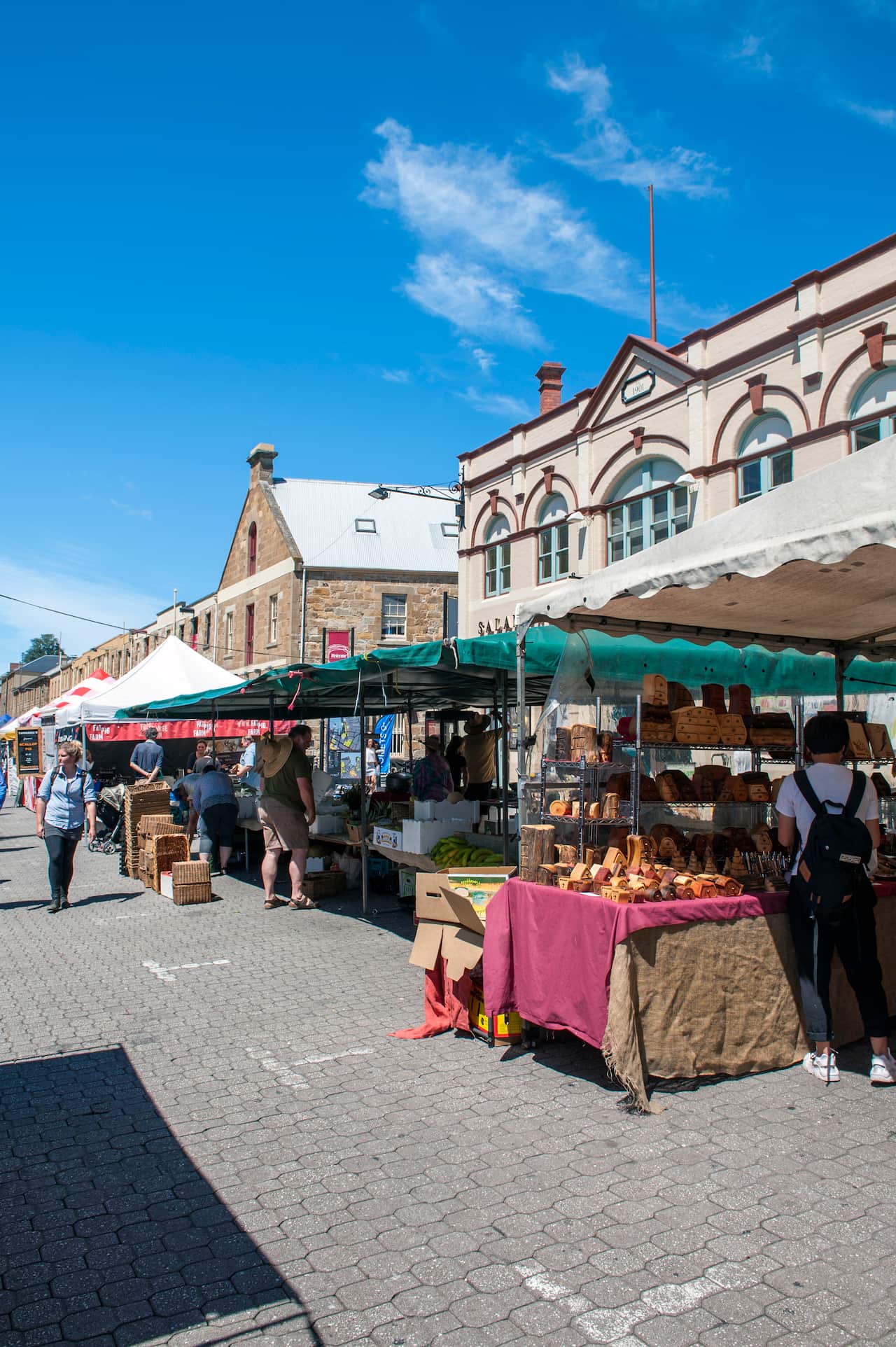 People browse market stalls set up in front of old buildings.