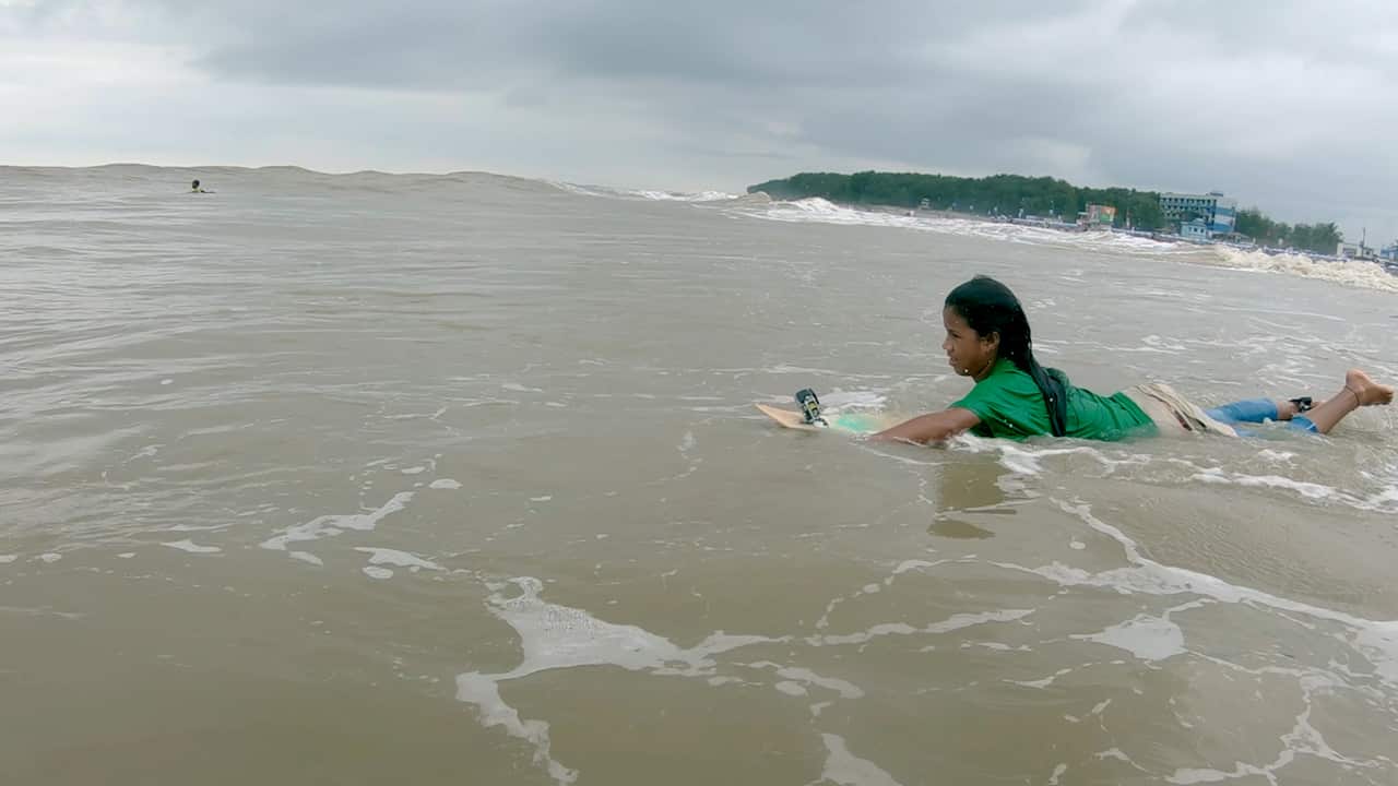 A girl paddling on a surfboard. 