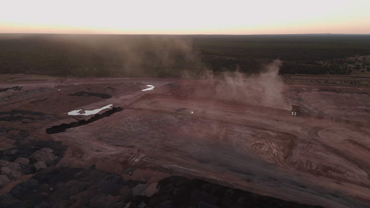 Clouds of dust rise up from the Earth at a coal mine.