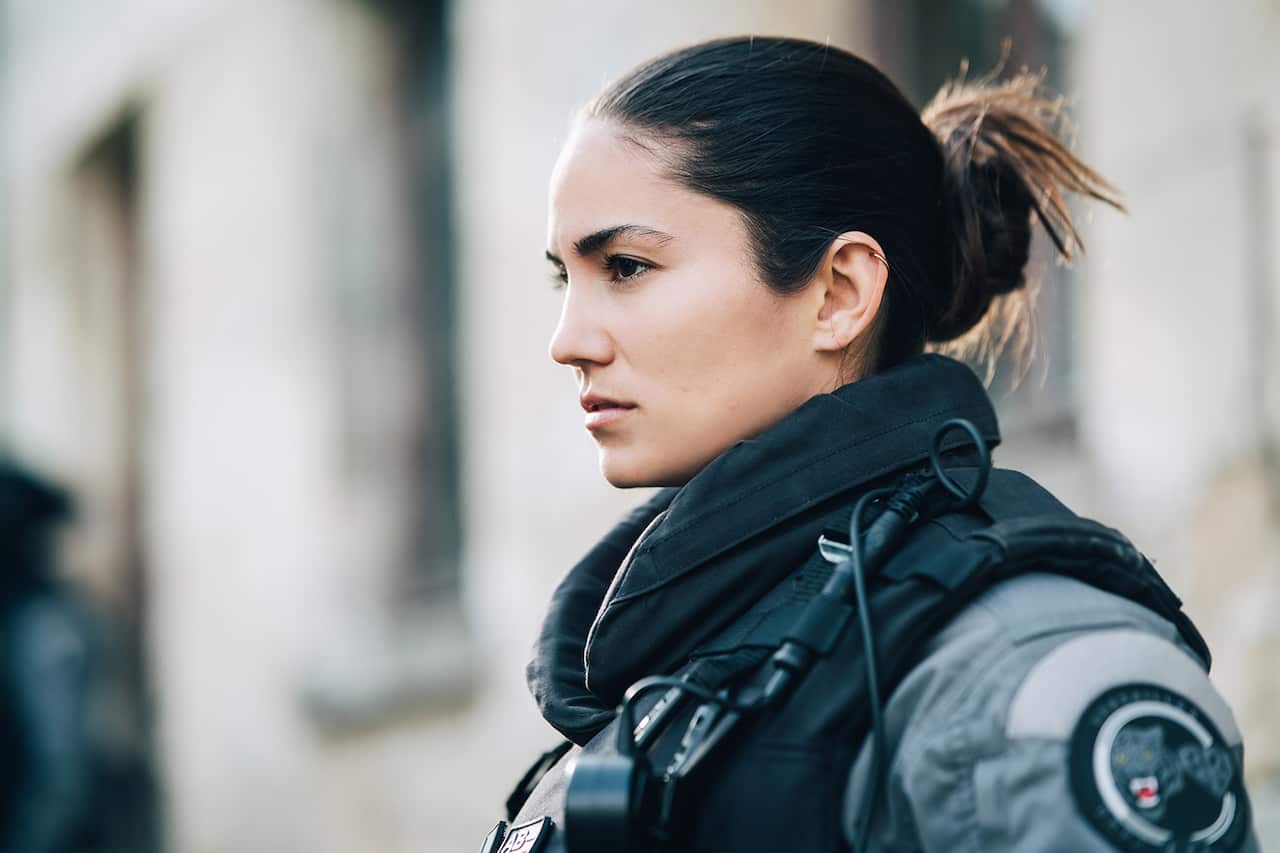 A woman with dark hair in police uniform and protective gear.