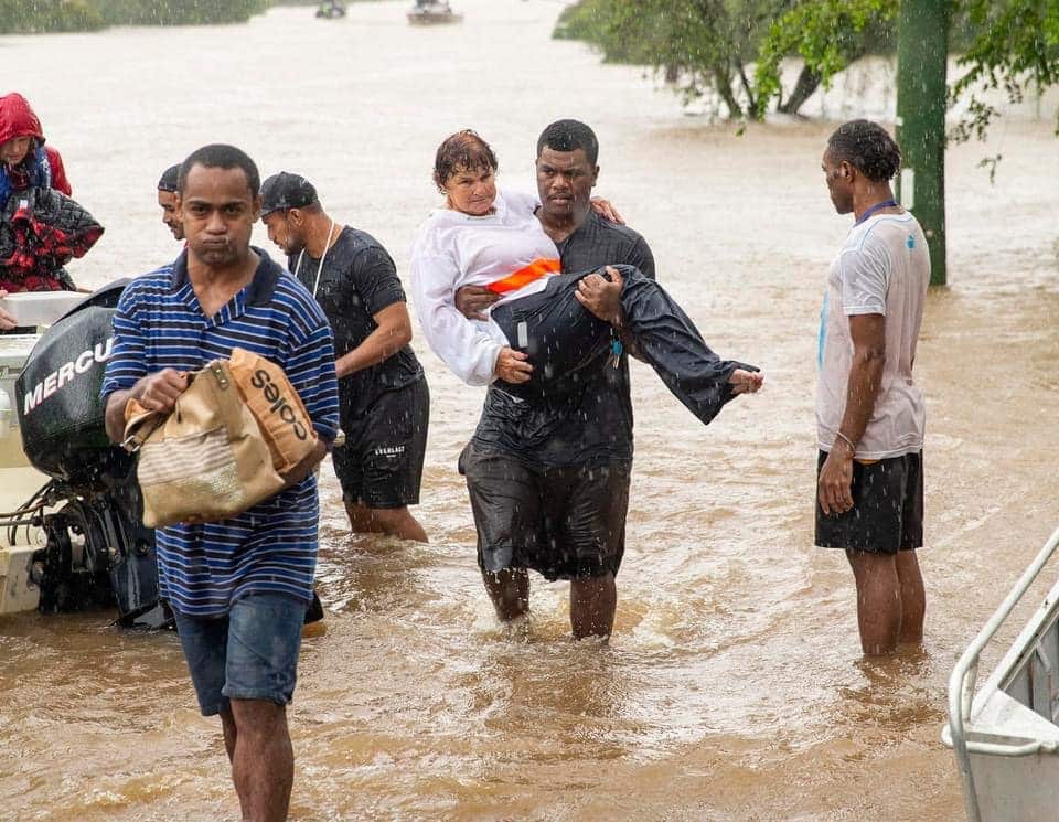 A team member carries an aged care resident from the RSL LifeCare to safety in Lismore, NSW.