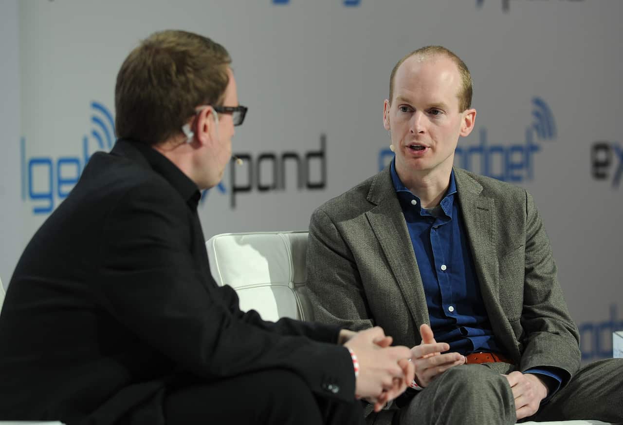 Two men are wearing suits, speaking at a convention 