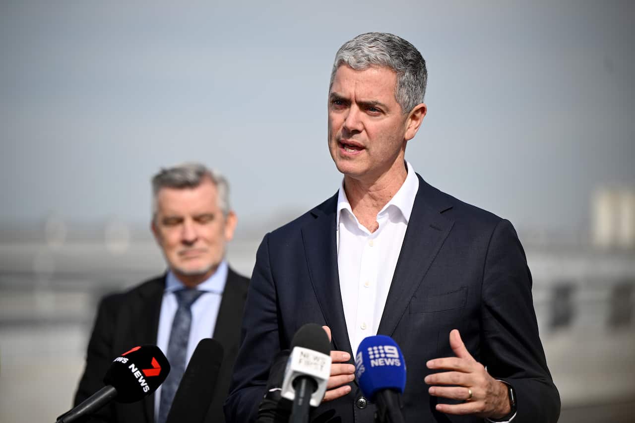 A man in a suit speaks to the media