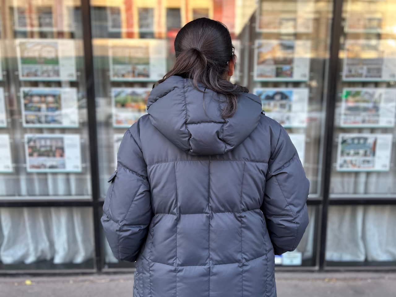 Priyanka looking in a real estate agent window.