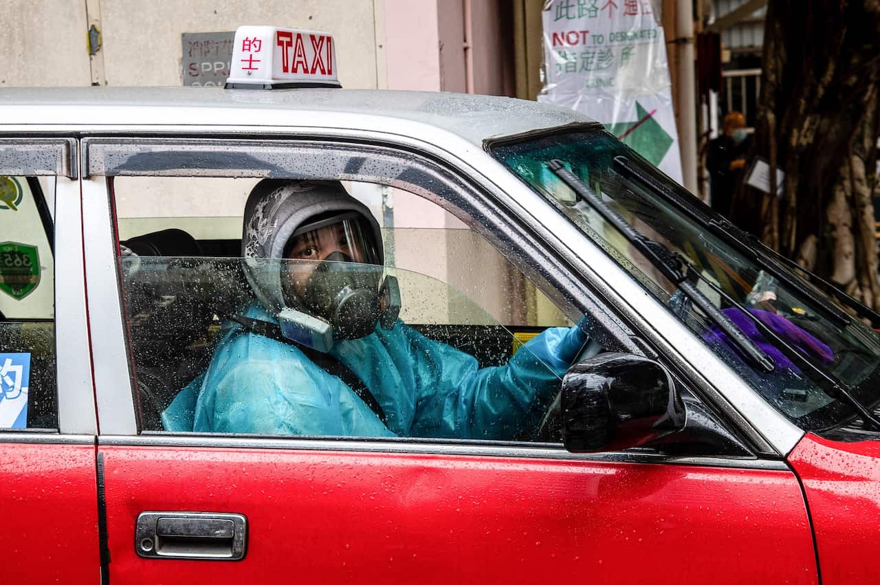 A taxi driver in Hong Kong wears PPE, including a gas mask.
