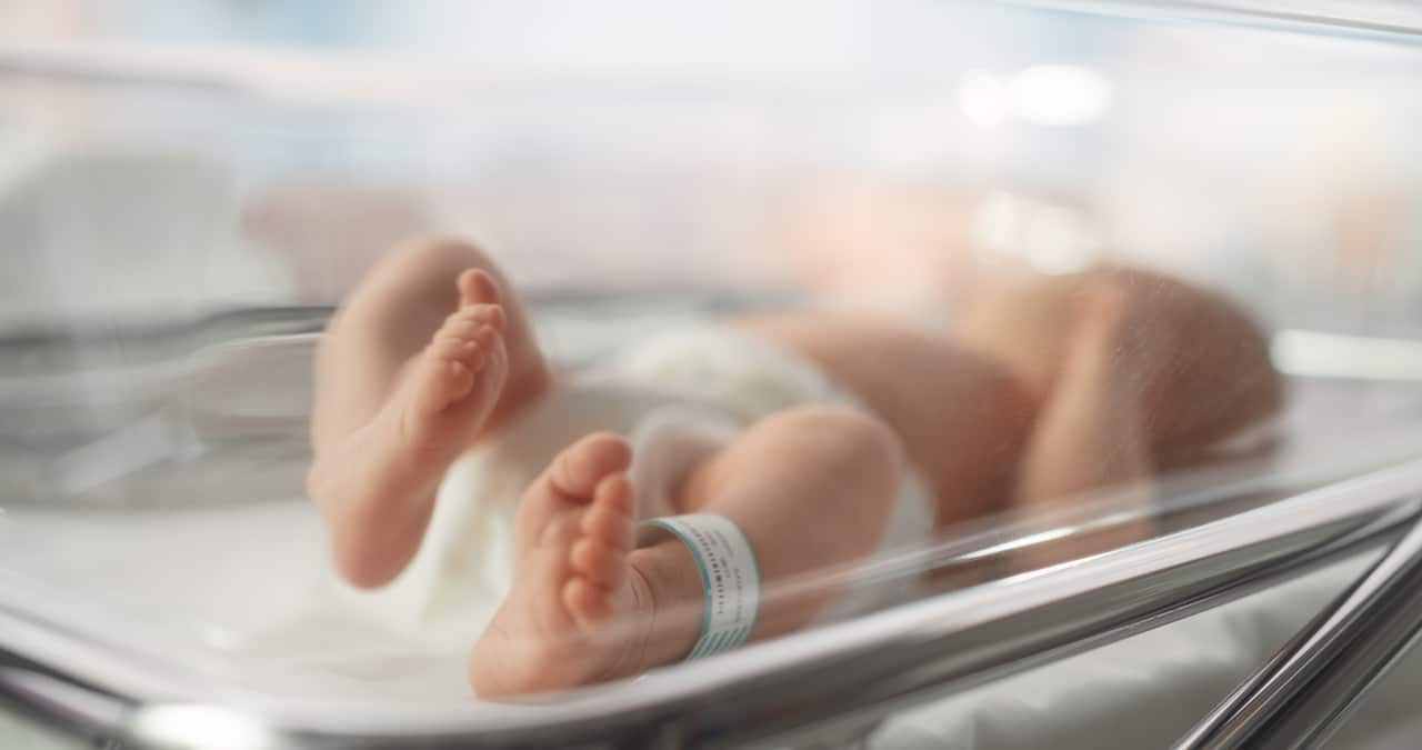 A newborn baby in a hospital crib.