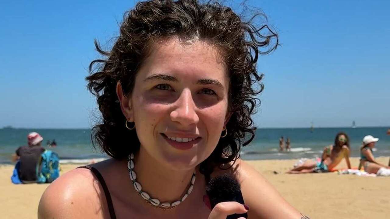 A woman in a bikini sitting on a towel at the beach.