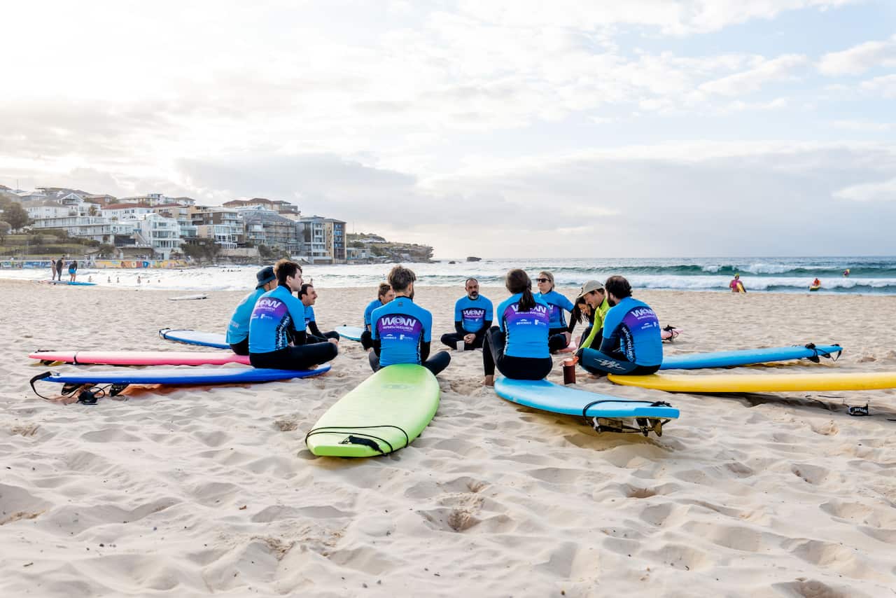 People sitting on surfboards in a circle at a beach.
