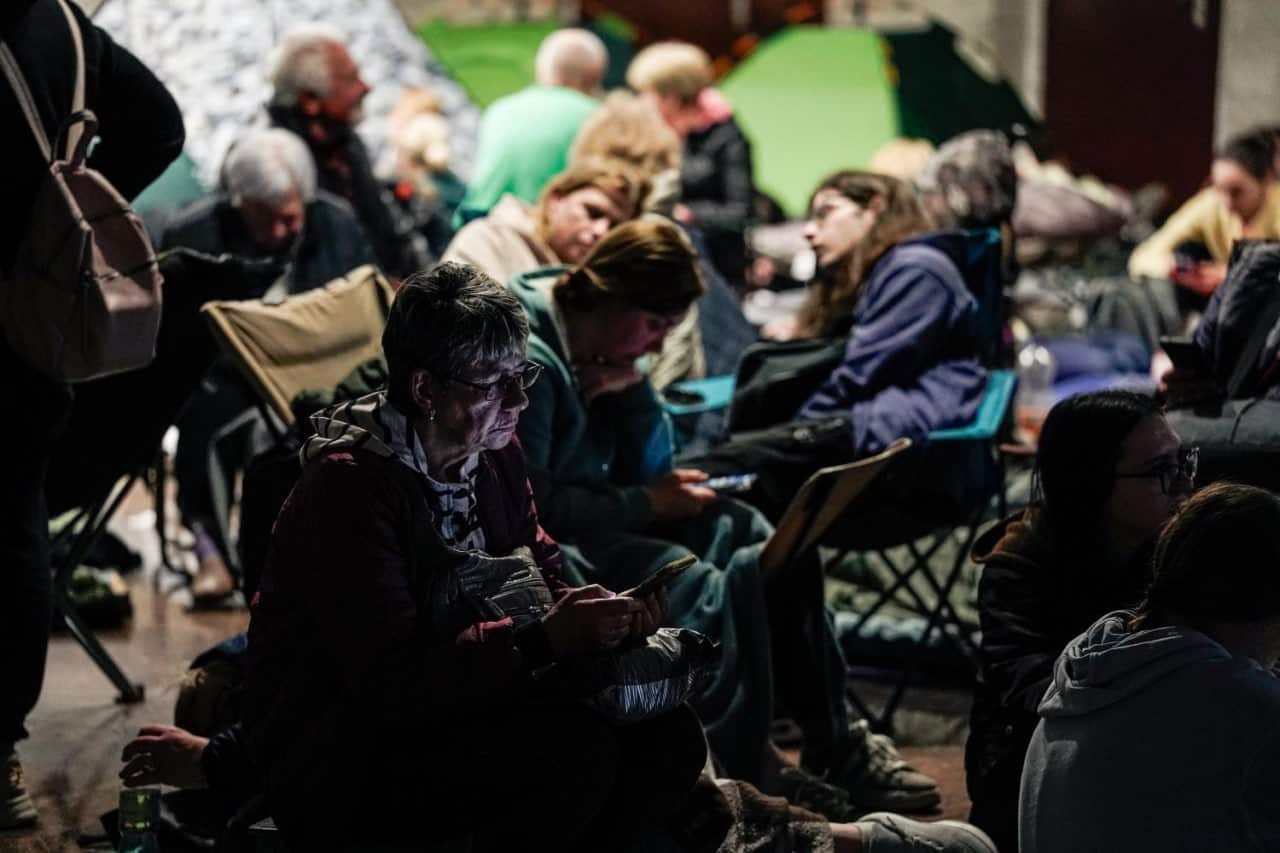 People sitting on camp chairs in an underground metro.