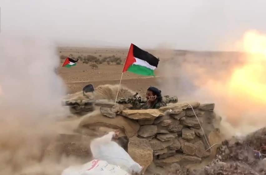 A person fires a rocket from a bunker made of rocks