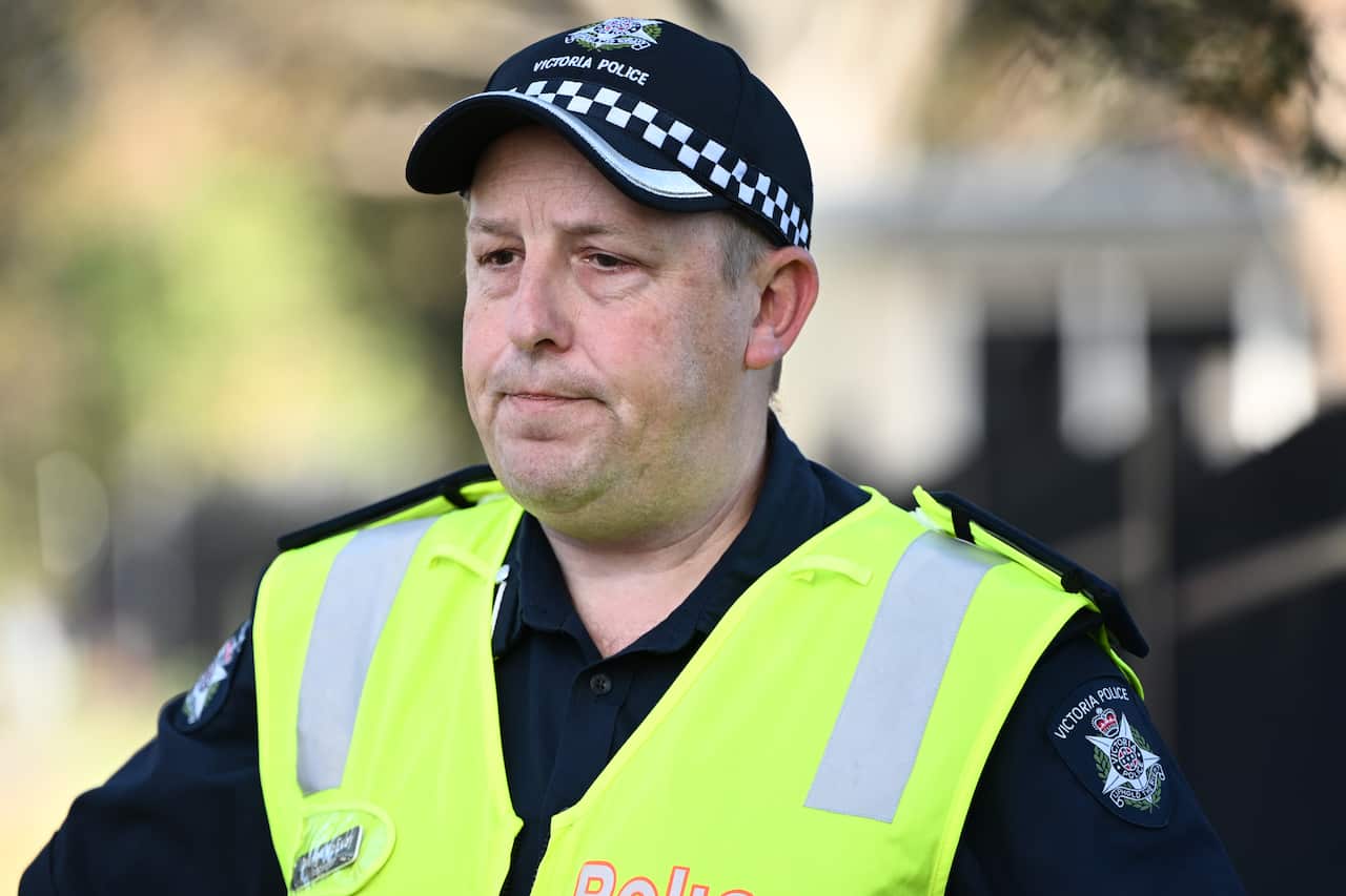 A police officer in hi-vis gear looks stern.