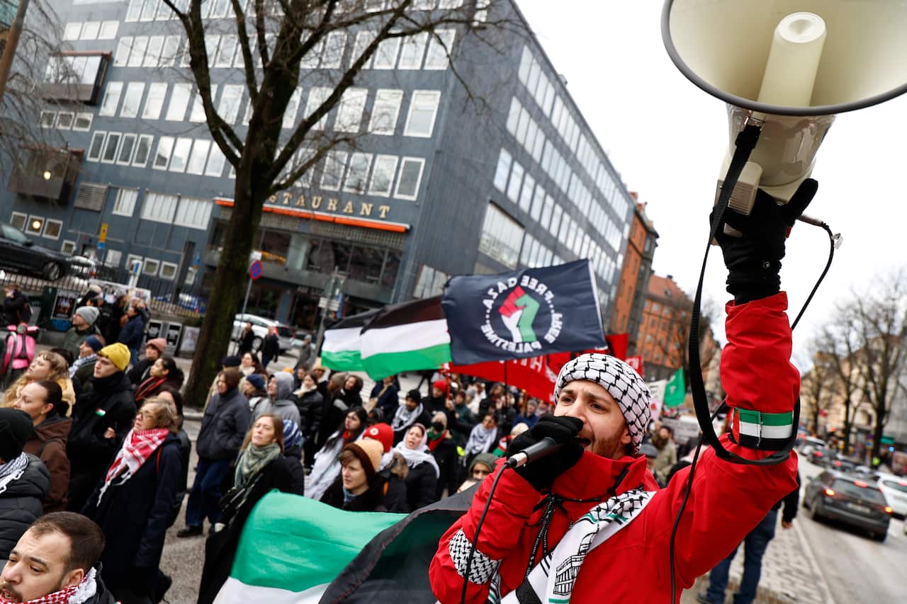 A group of protesters, some with Palestinian flags, one with a megaphone.