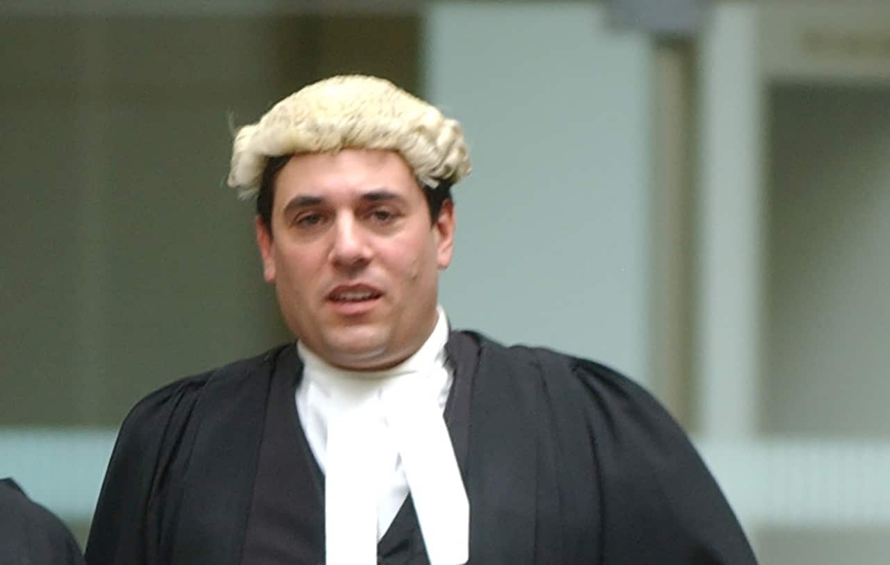 A man wearing a black judicial robe, collarette and a wig.