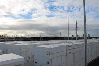 Rows of white cabinets with large transmission towers in the background.