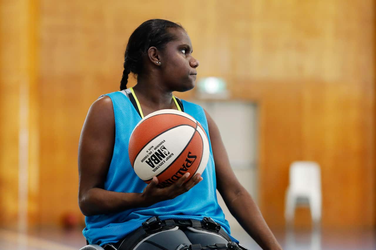 A woman in a sports vest holding a basketball