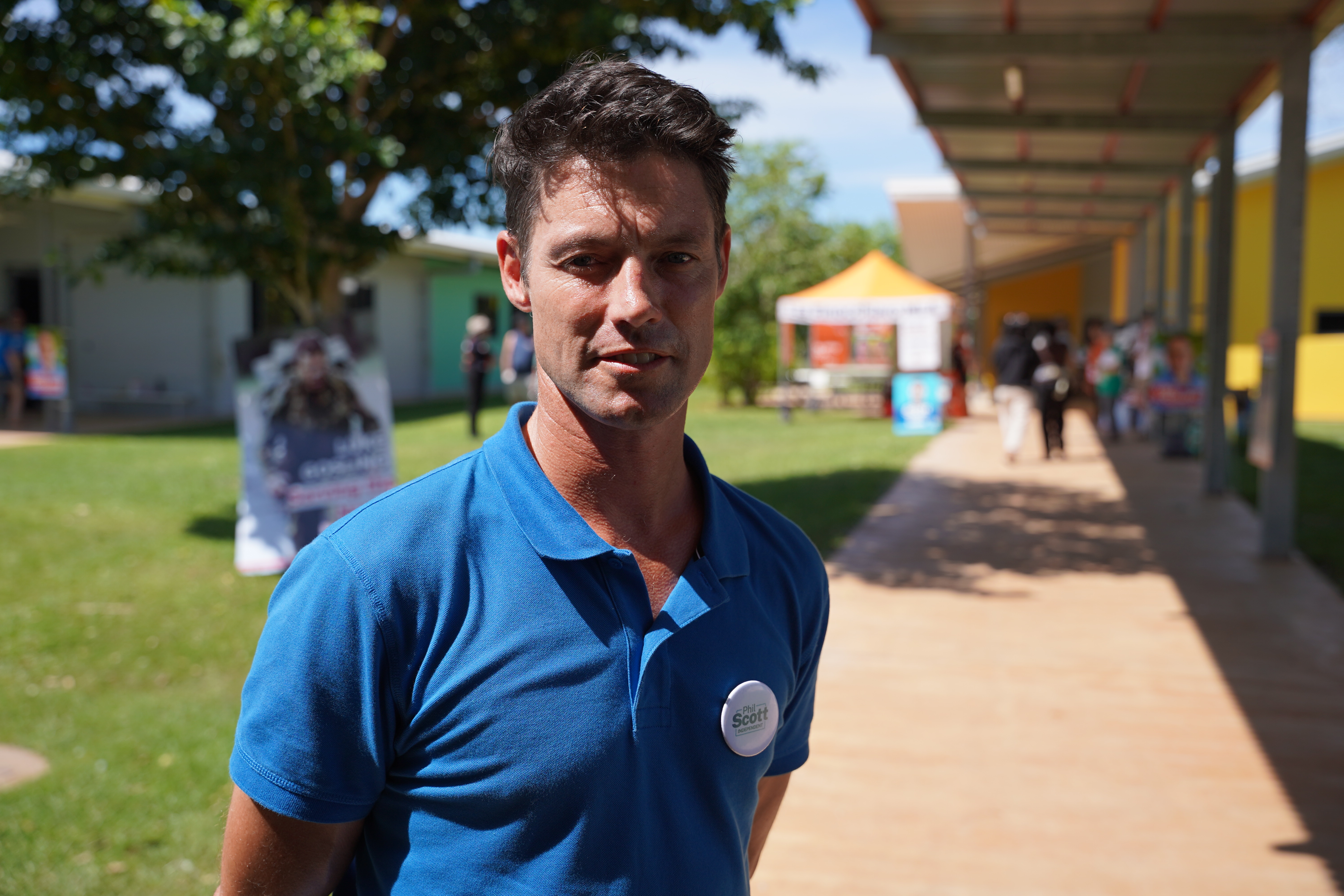 A man in a blue polo shirt standing outside a polling centre.