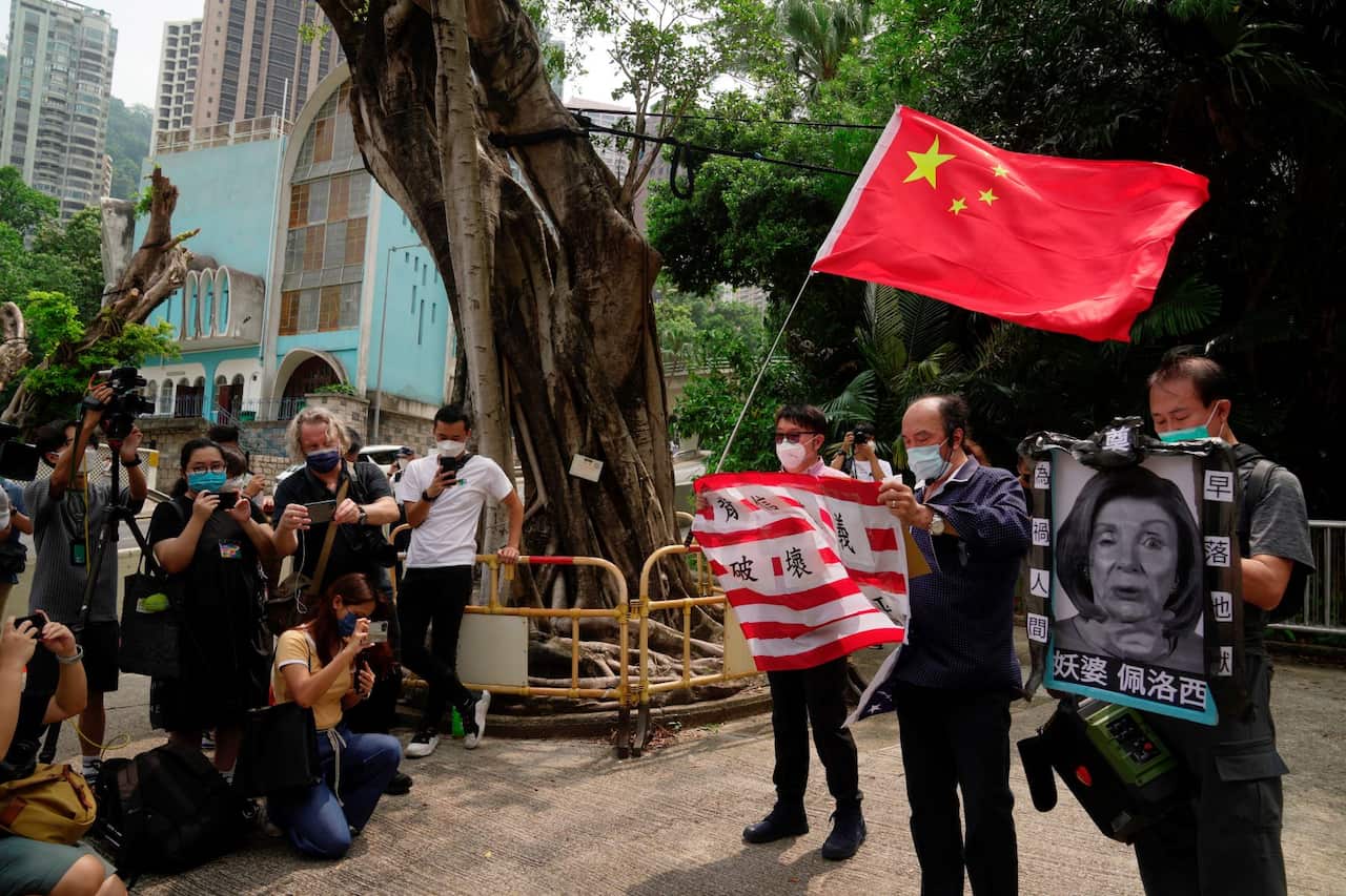 Pro-China supporters hold U.S. flag and a picture of U.S. House Speaker Nancy Pelosi during a protest outside the Consulate General of the United States in Hong Kong, Wednesday, Aug. 3, 2022.