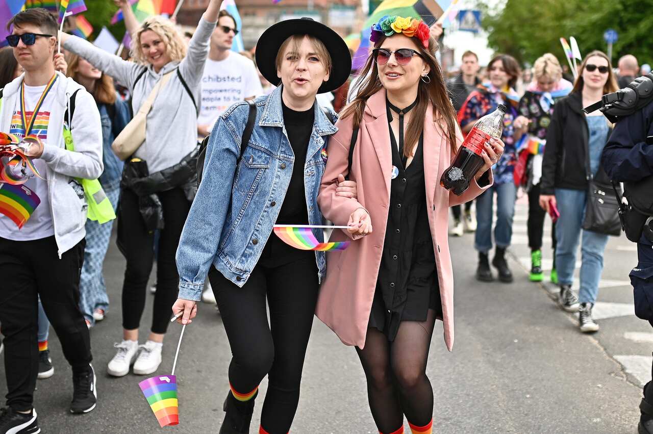 People smile and march waving pride flags.