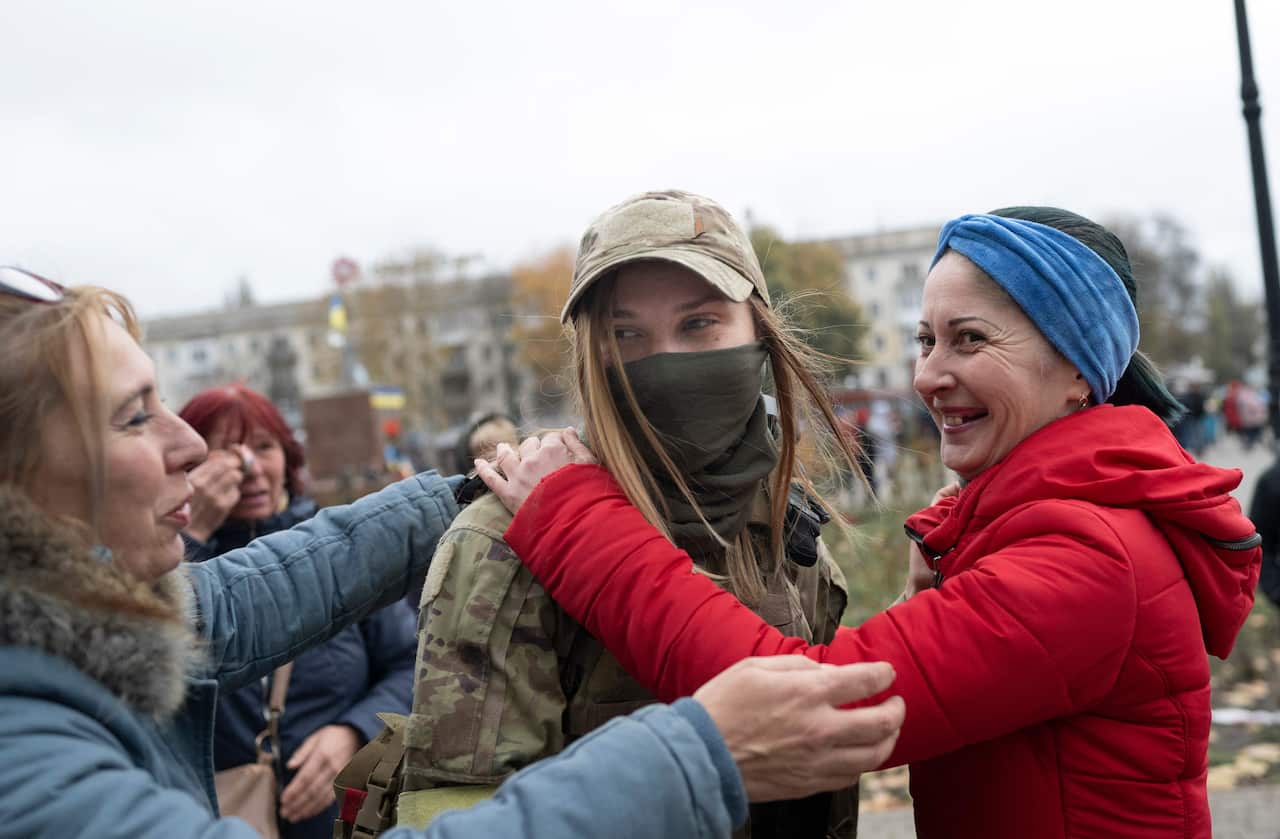 Two women hug a Ukrainian soldier in central Kherson.