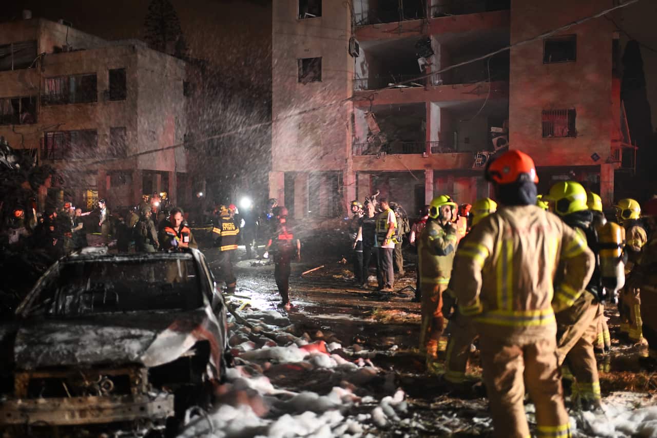 Firefighters spray foam over a burnt-out street.