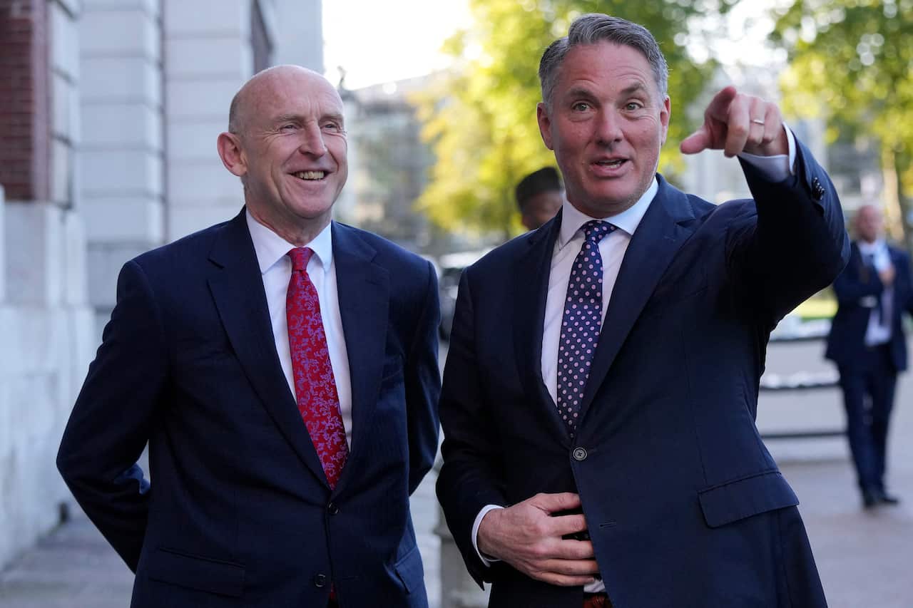 John Healy and Richard Marles smile next to each other in suits outside
