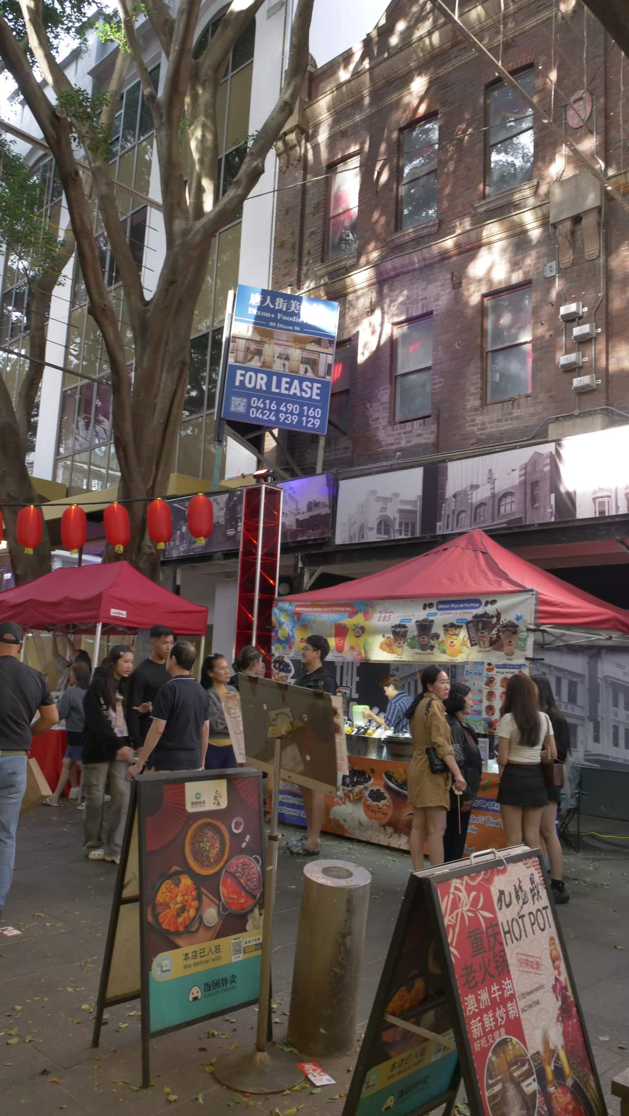 People standing in front of market stalls set up in front of a building for lease.