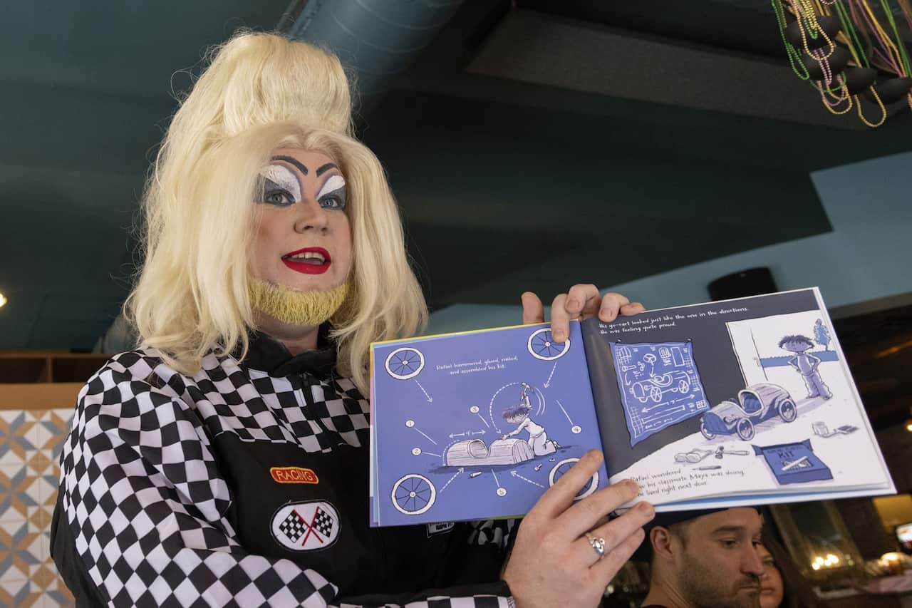 A drag queen reading a book to an audience. 