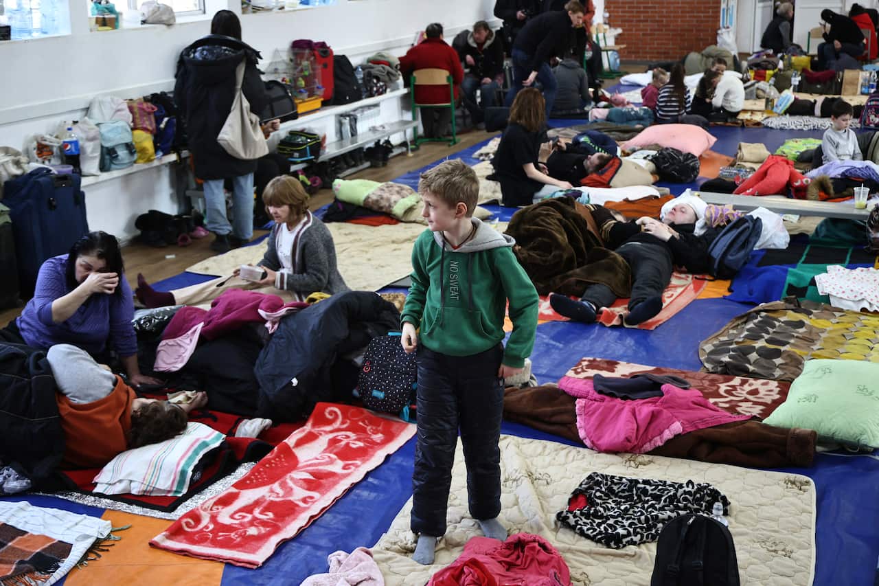 People are seen in a temporary accommodation facility for the evacuated in a local secondary school named after Donat Patrycha in the urban settlement of Nikolskoye (former Volodarskoye).
