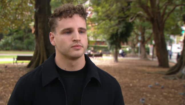A young man wearing a black top in a park
