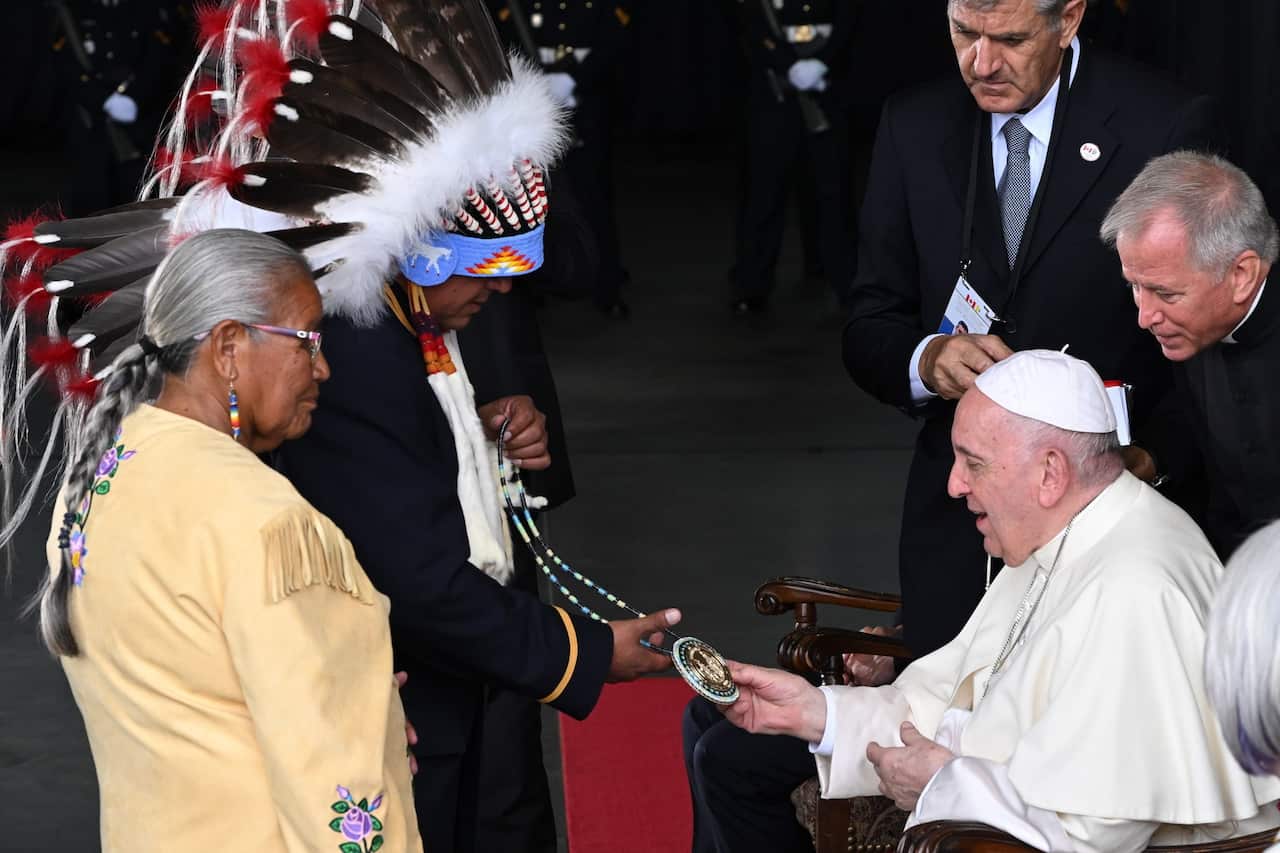 Indigenous leaders show Pope Francis a medallion necklace. 