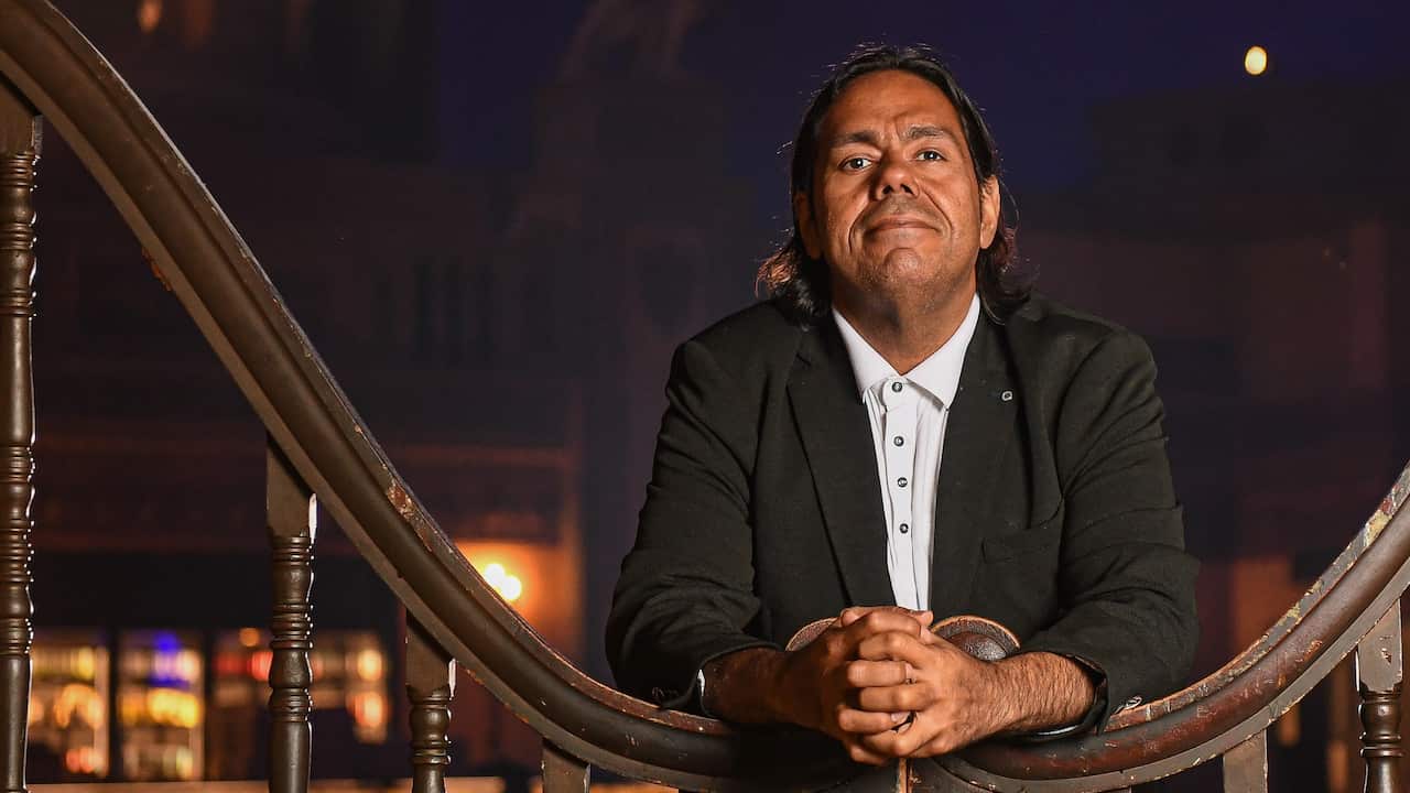 A mean wearing a suit posing for a photograph