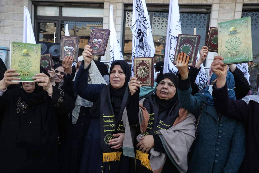 People standing outside holding up Quran