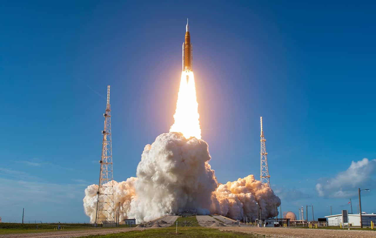 A spaceship lifts off from a launchpad leaving exhaust fumes behind