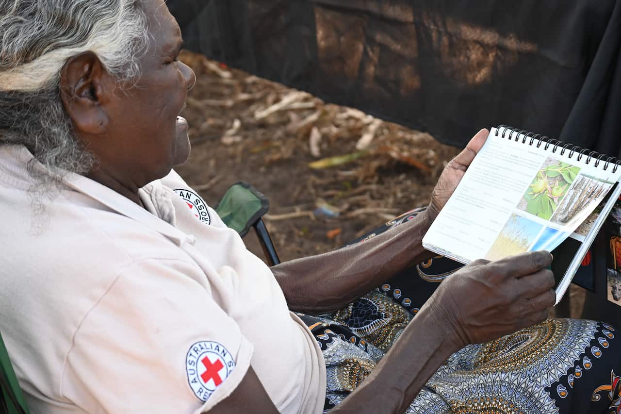 Senior Tiwi woman and Jikilaruwu elder Molly Munkara looks through a book on medicinal plants created by Tiwi leaders