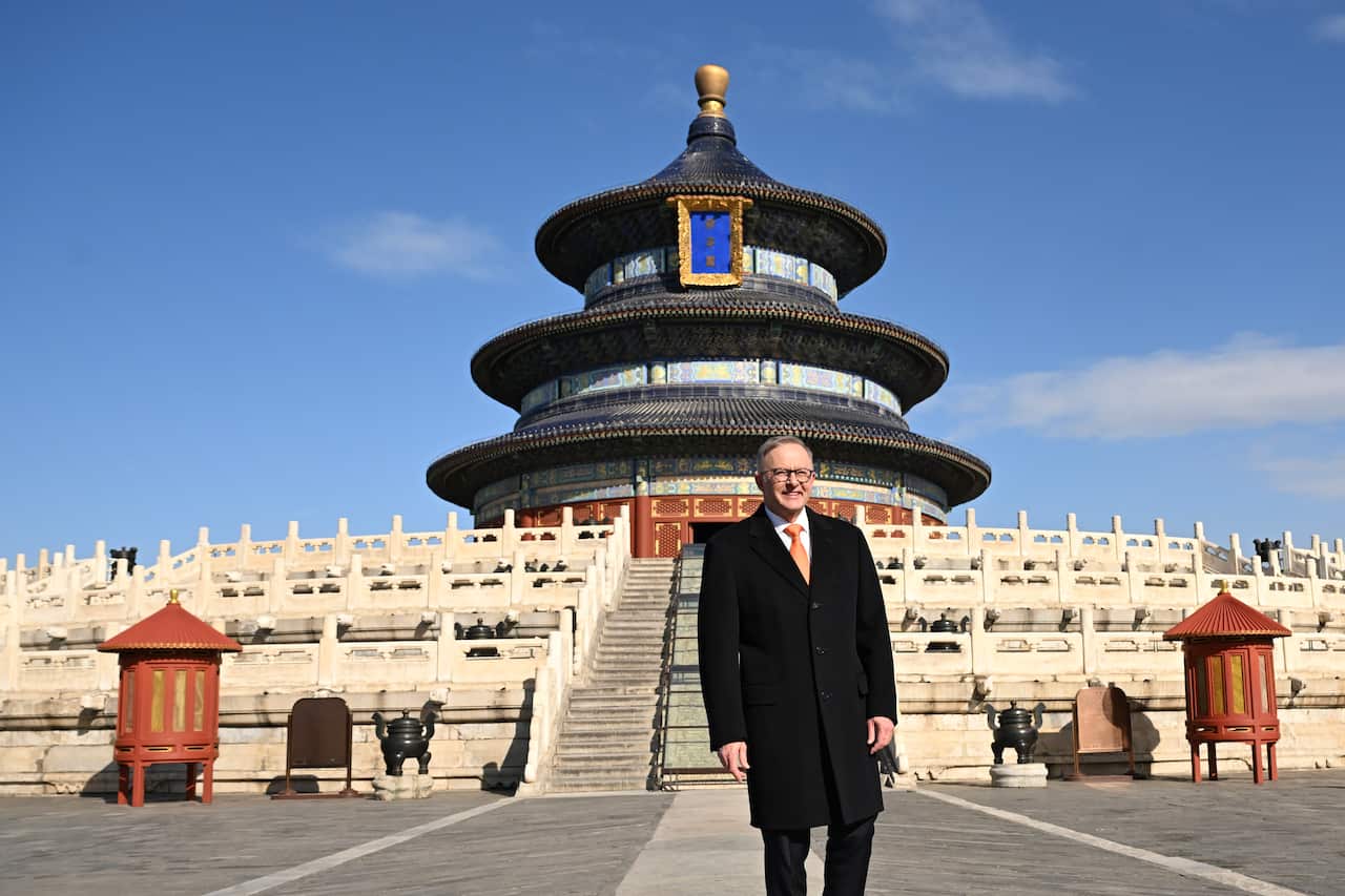 A man wearing a black coat in front of a Chinese temple