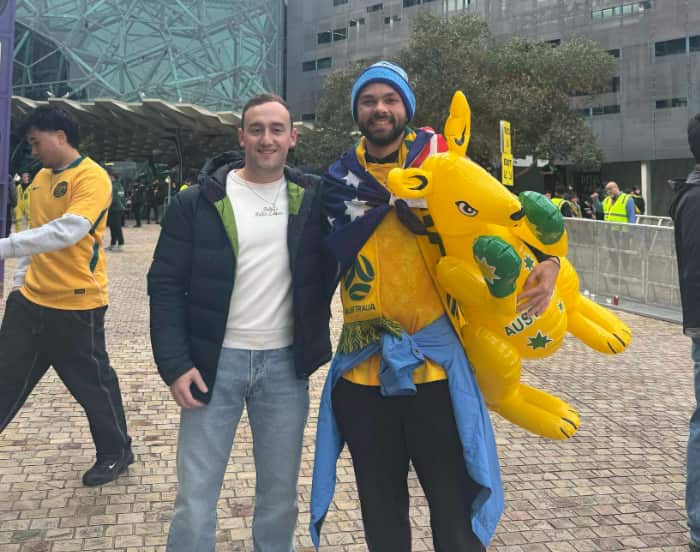 Two men smiling for a photo. One is holding a blow-up kangaroo.