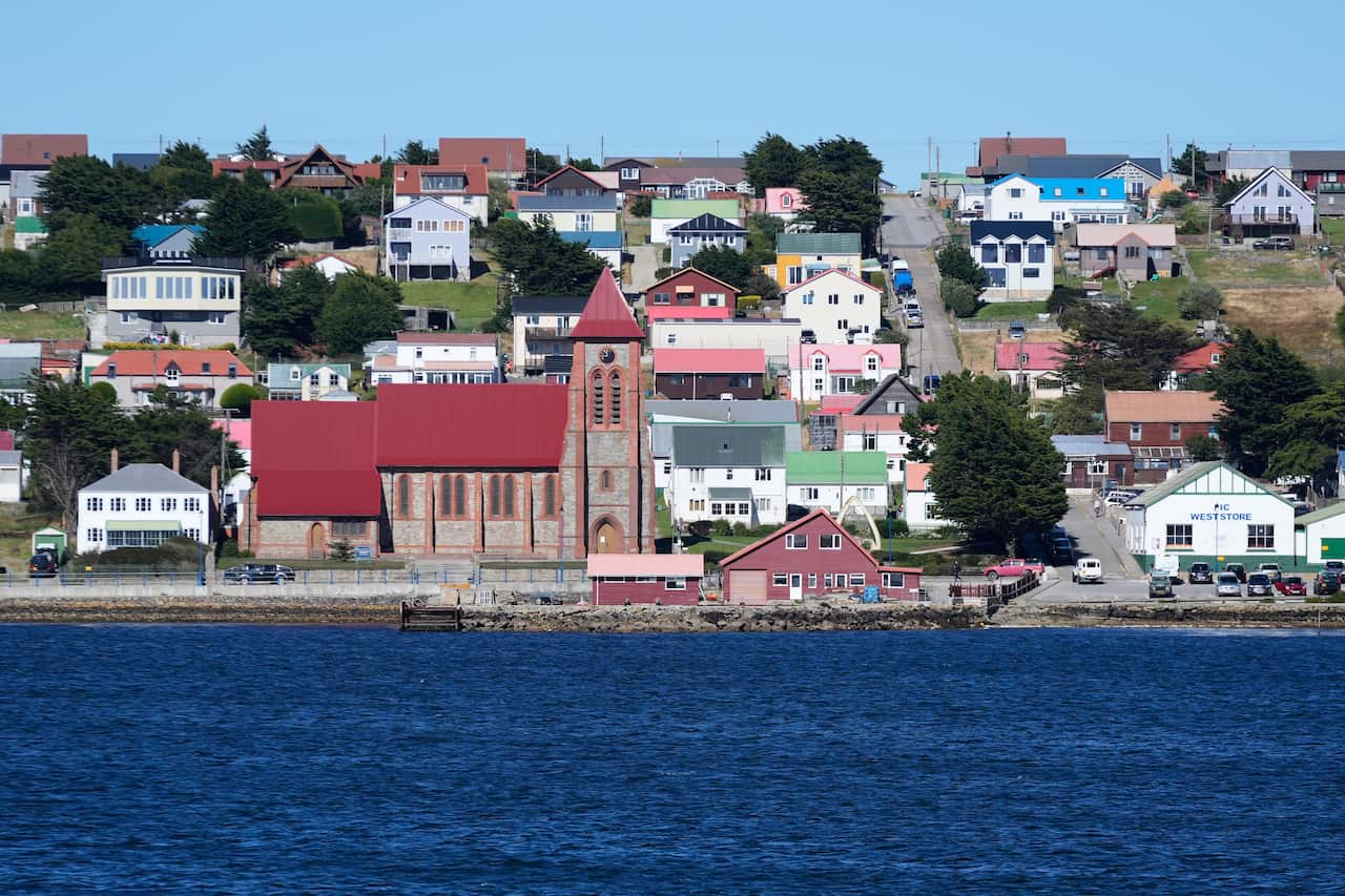 Suburban houses on a hill look over the ocean.