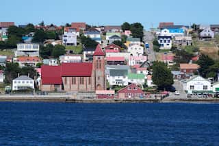 Suburban houses on a hill look over the ocean.